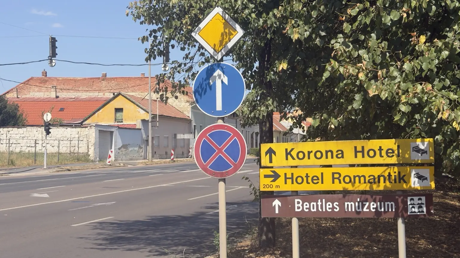 Korona Hotel, Hotel Romantik és Beatles múzeum feliratú irányjelzők több közlekedési tábla mellett